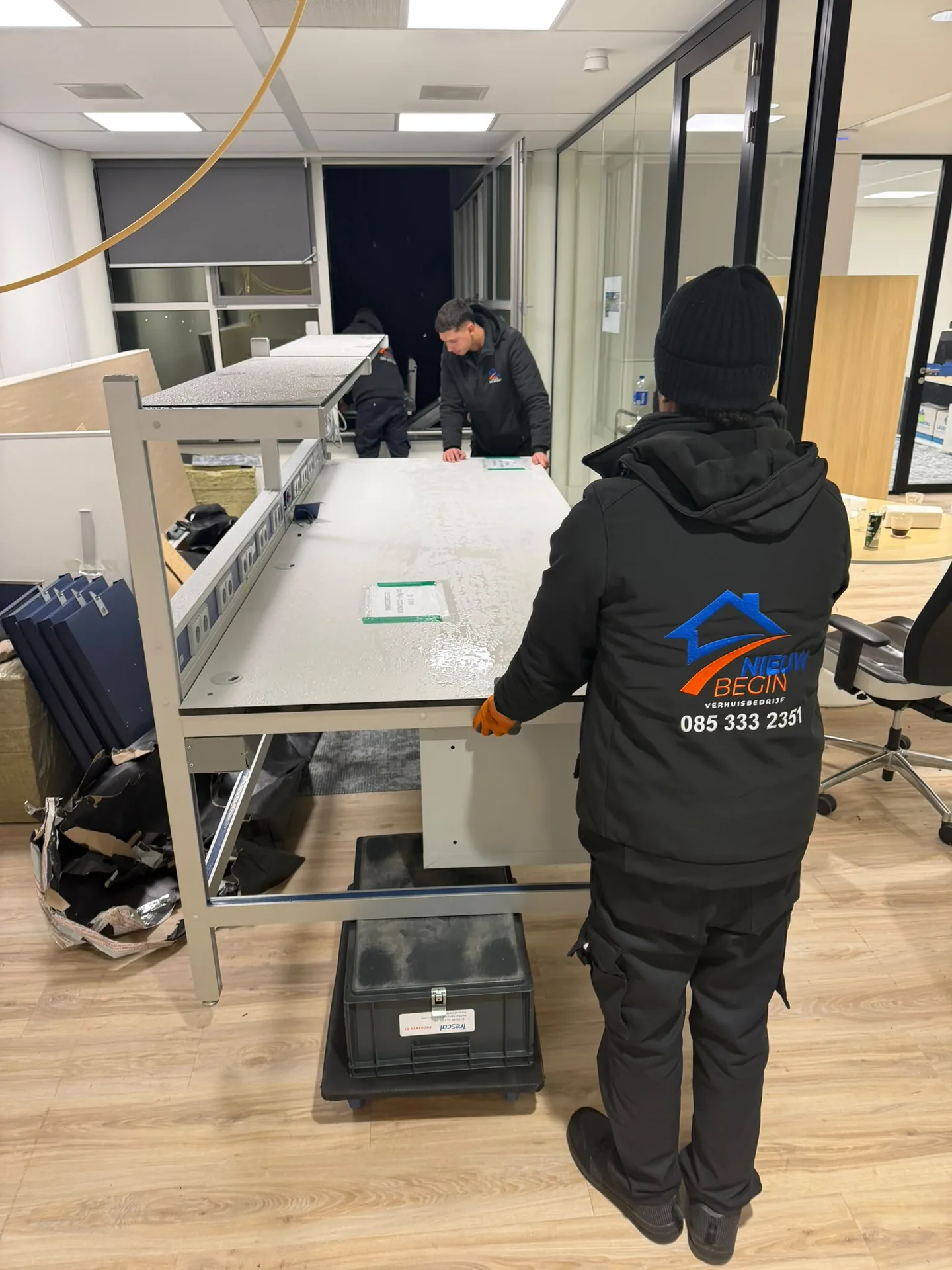 Verhuizer van Nieuw Begin monteert een bureau op kantoor