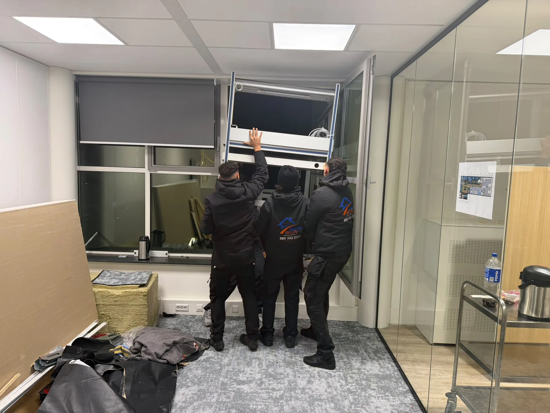Drie verhuizers van Nieuw Begin halen een kantoor leeg bij het raam