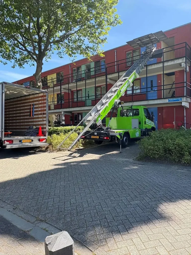Verhuislift tegen een appartementencomplex, met de wagen ervoor