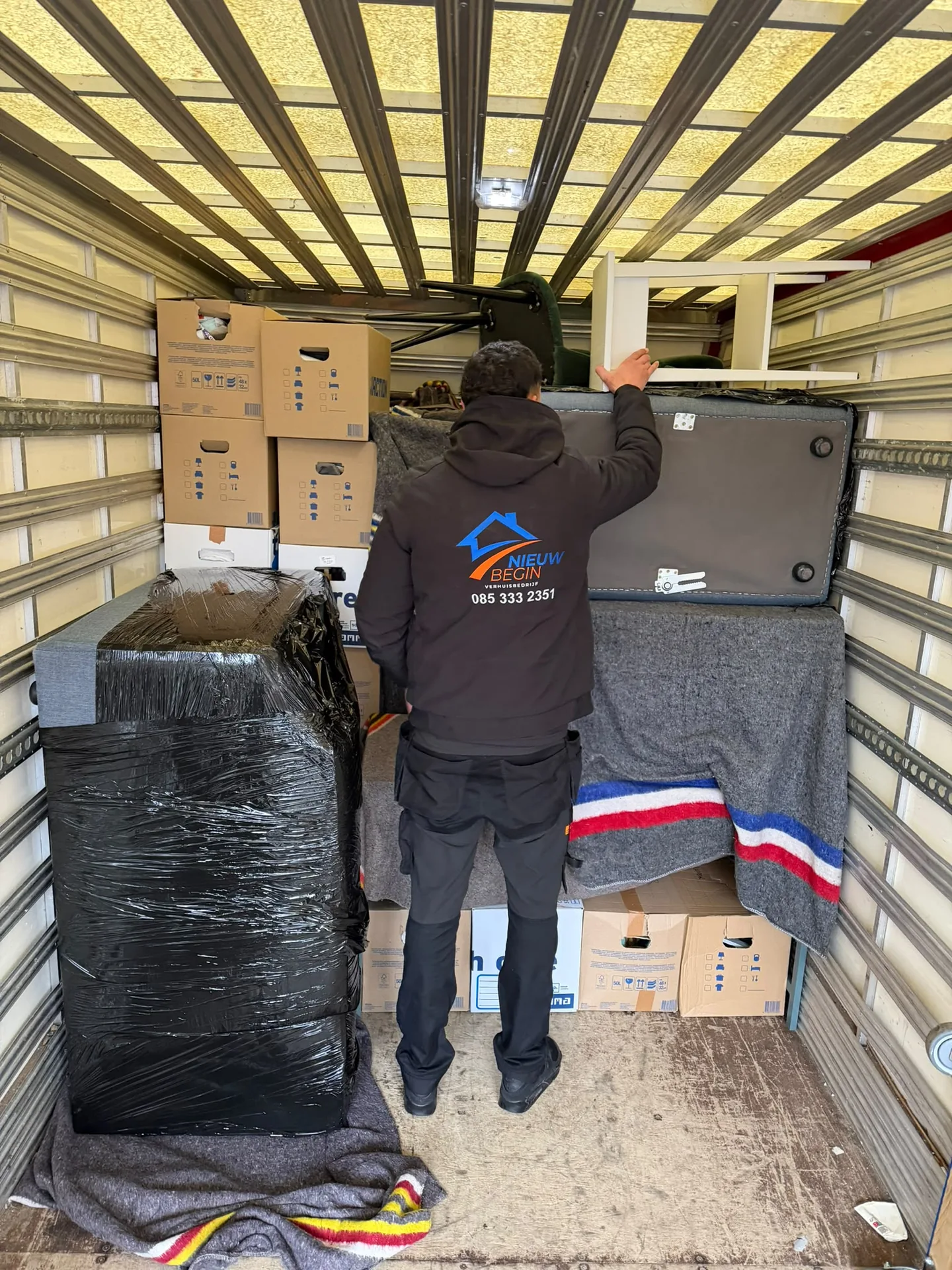 Volgeladen wagen van Nieuw Begin met dozen en meubels in folie