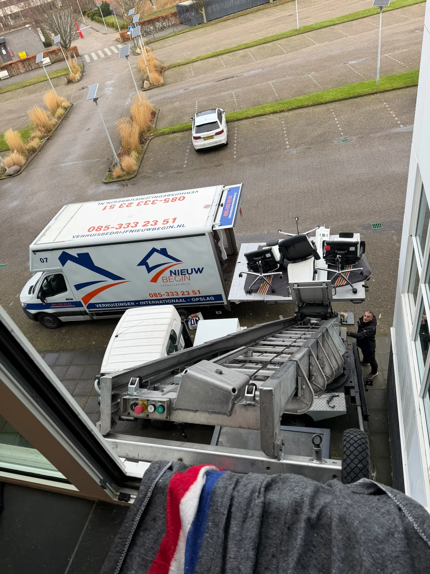 De verhuiswagen en de verhuislift van Nieuw Begin bij een kantoorpand, van bovenaf gezien