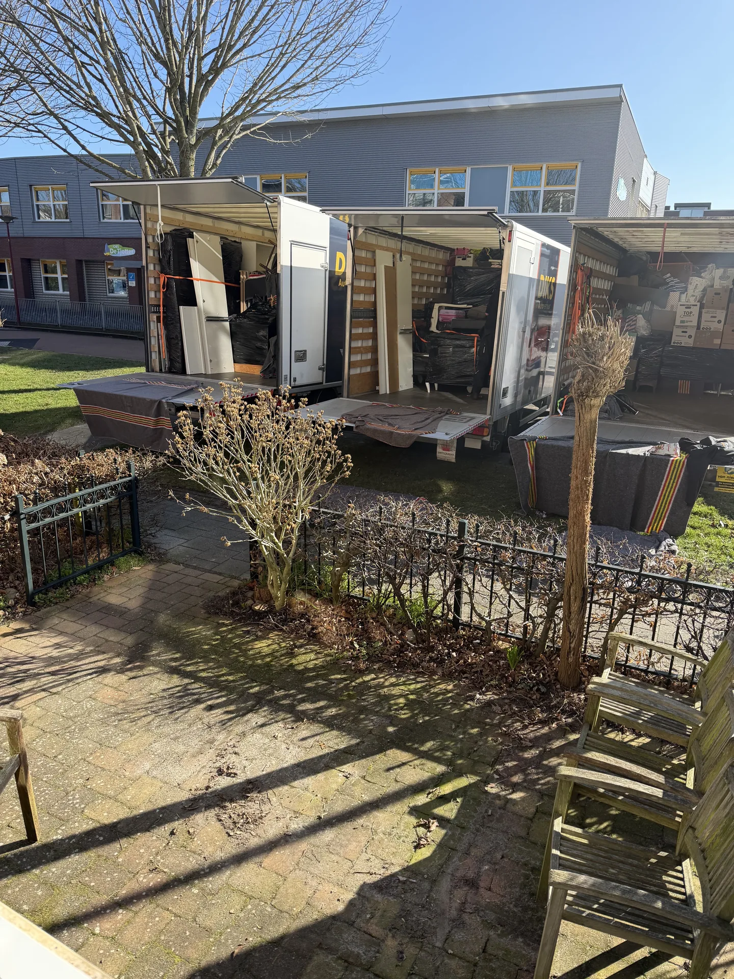 De verhuiswagen van Nieuw Begin met de laadklep open bij een woning met tuin