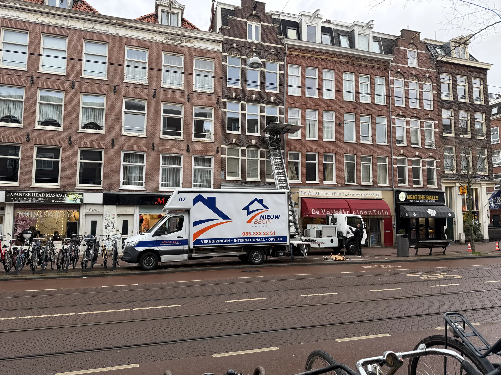 De verhuiswagen en de verhuislift van Nieuw Begin in een stadsstraat